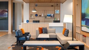 A modern living room with a sofa, armchairs, and a coffee table. There is a kitchen area with cabinets and a dining table. - Hyatt House Fresno Campus Pointe (Fresno)