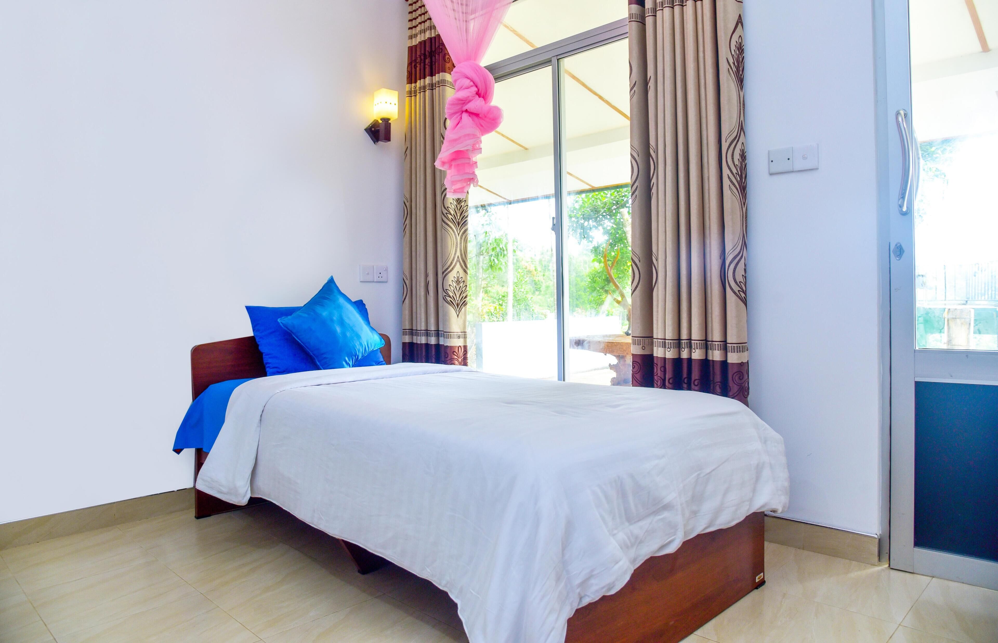 A bedroom with a bed, a nightstand, a window with curtains, and a door.