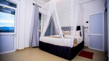 A bedroom with a bed under a canopy, a red rug, and a view of the outdoors.