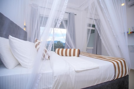 A bed with white bedding and striped pillows, a grey headboard, and a canopy.