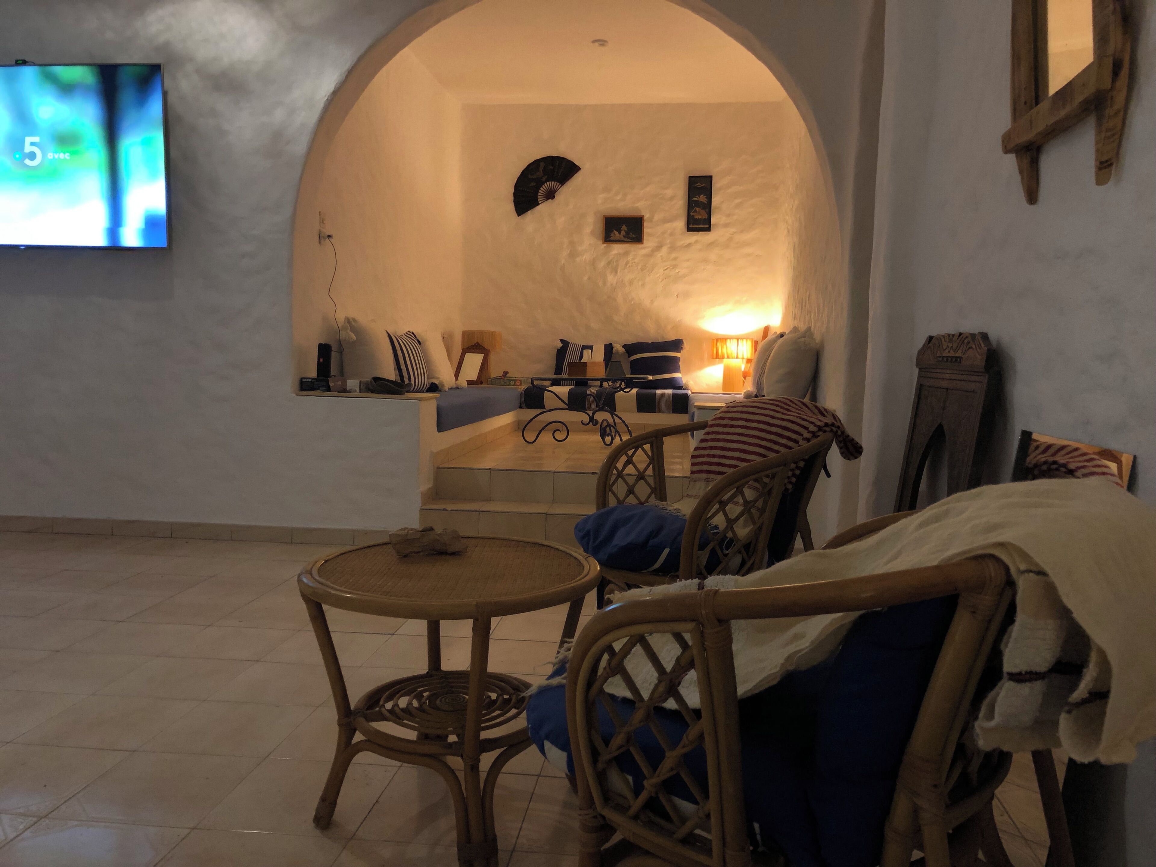 Een gezellige woonkamer met een televisie, een bank, een fauteuil en een klein tafeltje.