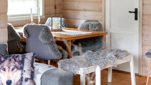 A cozy cabin interior with a wooden ceiling, a dining table, a sofa with a fluffy throw, and a white door. - Stavtjørn Apline lake Haven (Vikeså)