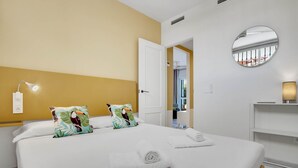 A neatly made bed with two pillows, a bedside lamp, and a rolled towel.