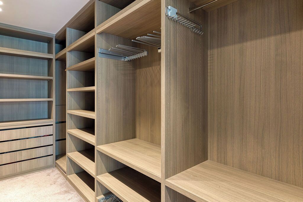 A walk-in closet with multiple wooden shelves and a metal drying rack.