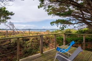 A wooden deck with a railing, overlooking a coastal landscape with trees and a view of the sea. - Charming House by the Sea (Gulf) (Sarzeau)