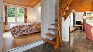 Um quarto com cama, escada de madeira, escrivaninha e cadeira.