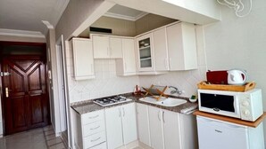 A compact kitchen with white cabinets, a gas stove, a microwave, and a built-in oven.