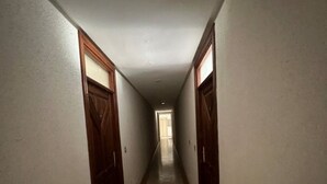 A narrow hallway with tiled flooring and wooden doors on both sides.