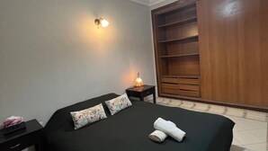 A hotel room with a bed, a nightstand, a lamp, and a wardrobe.