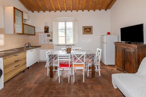 Una cocina compacta con una mesa de comedor, sillas, un refrigerador y un televisor.
