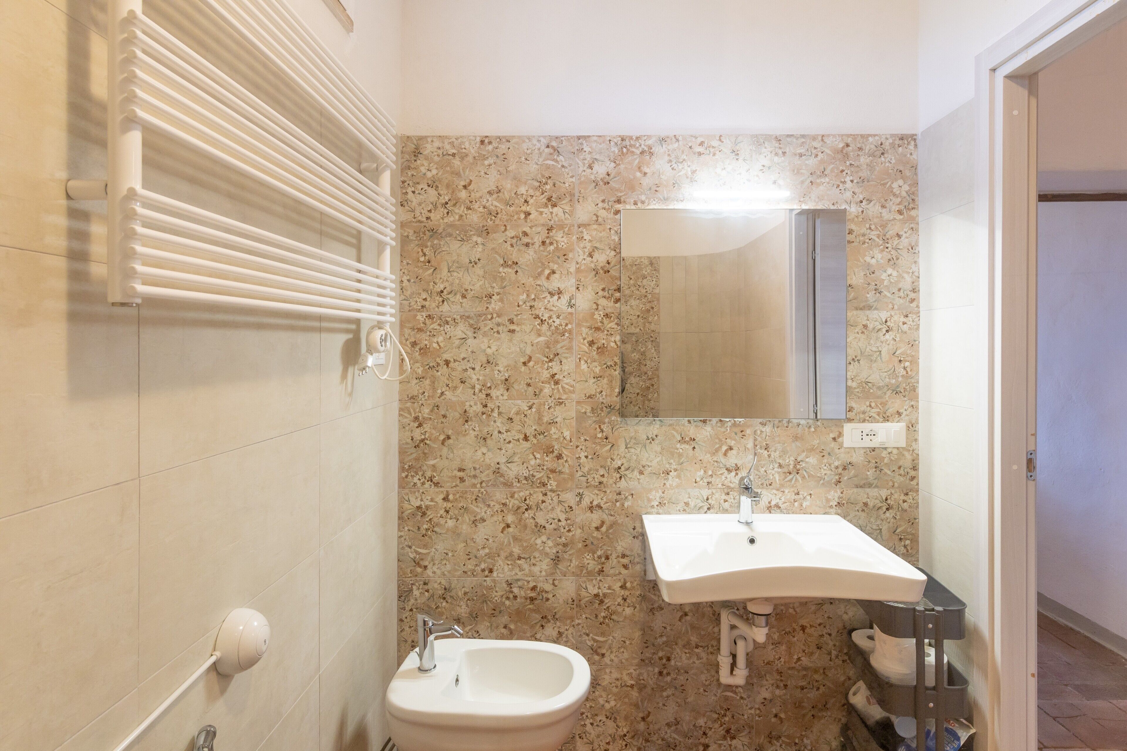 Ein Badezimmer mit einer Bidet, einem Waschbecken, einem Spiegel und einem Handtuchhalter.