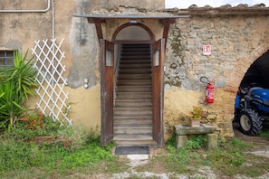 A stone staircase leading to a doorway, a fire extinguisher on the wall, and a blue vehicle parked outside.