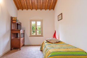 Une chambre à coucher avec un lit, une fenêtre, une commode en bois et une porte.