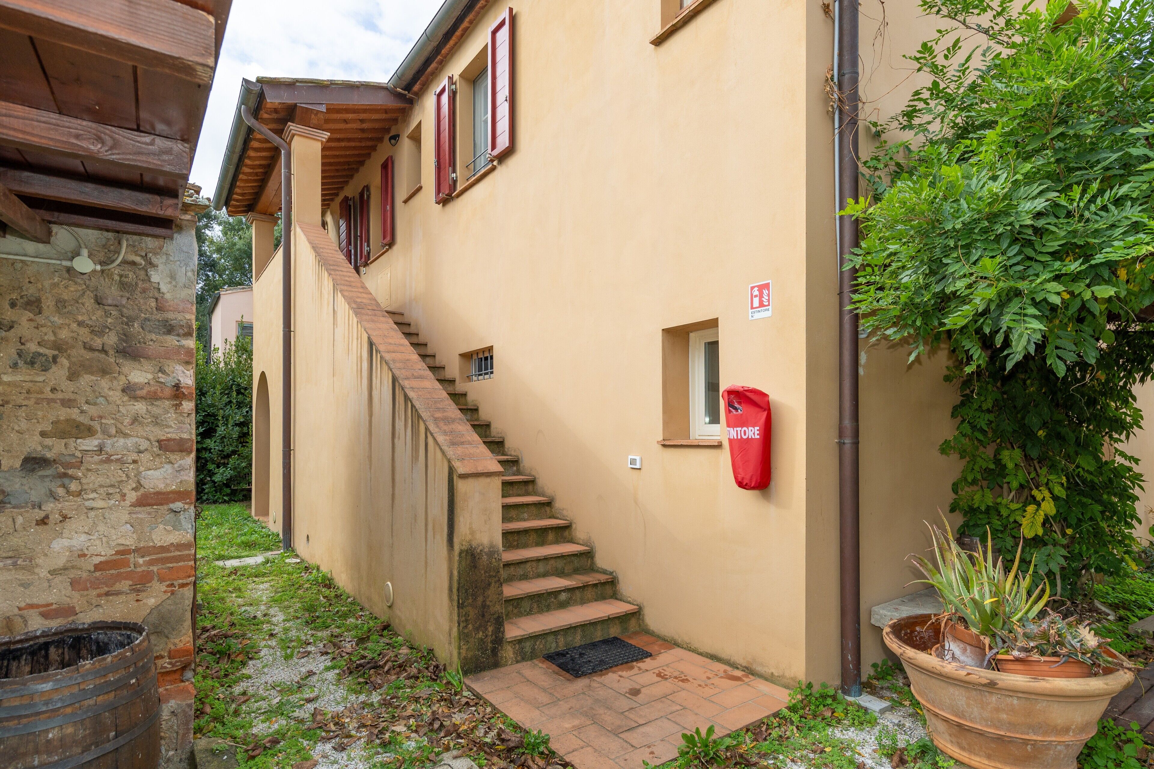 A building with a staircase leading to an upper level, a red mailbox, and a potted plant.