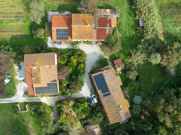 Vue aérienne d’un quartier résidentiel avec trois maisons, chacune dotée d’un toit en pente et de panneaux solaires.