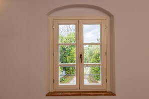 Une porte à deux battants, dotée d’une poignée en laiton, encastrée dans un mur sobre, avec une petite fenêtre au-dessus.