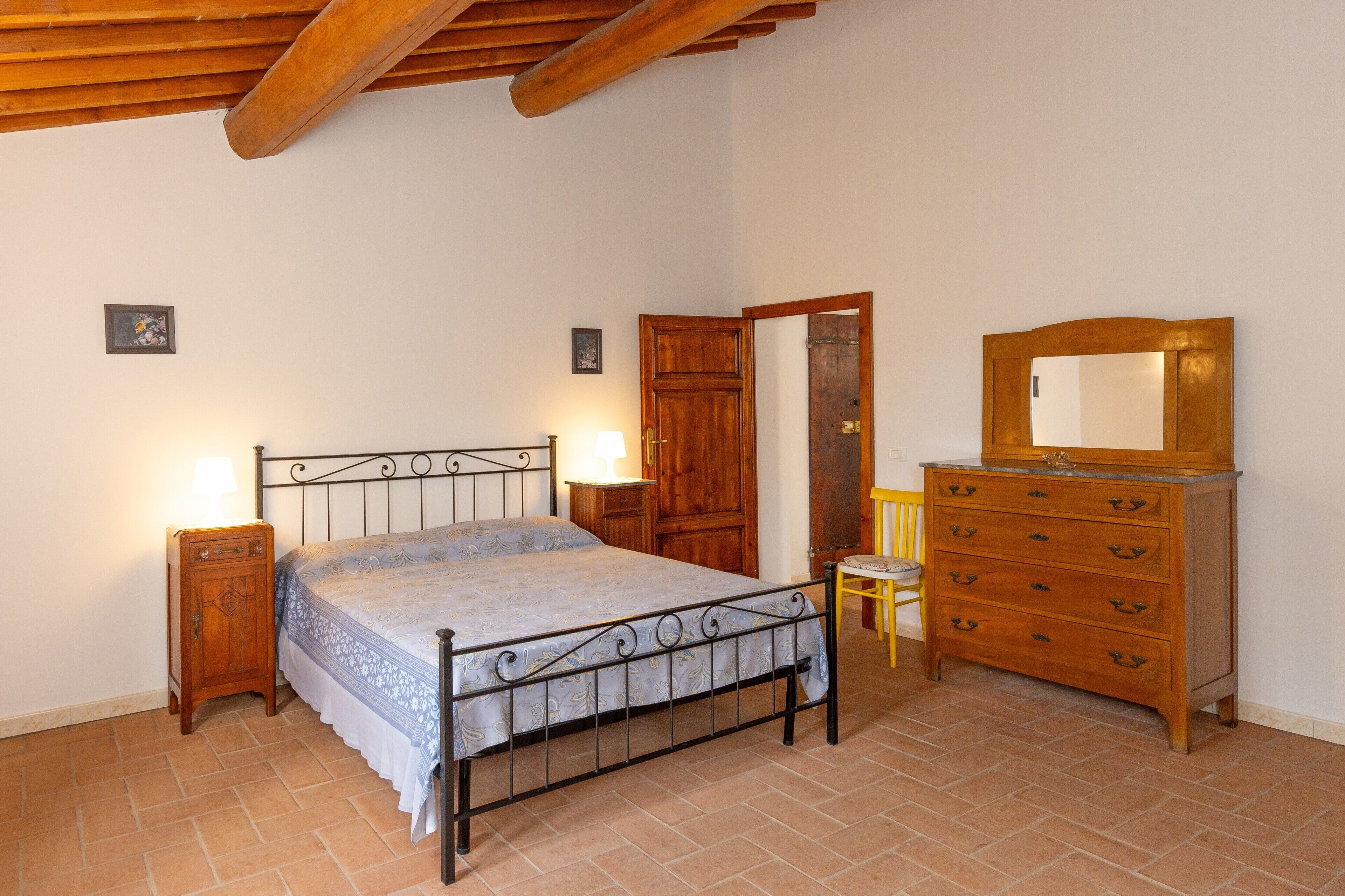 Ein Schlafzimmer mit einem Metallbettgestell, einem Holzschrank und einer Holztür.