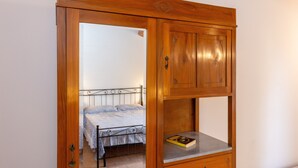 Une chambre à coucher avec un lit, une armoire en bois et une petite étagère sur laquelle se trouve un livre.