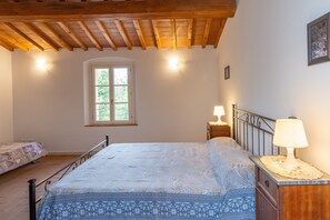 Ein Schlafzimmer mit Bett, Nachttisch, Lampe, Fenster und Holzboden.