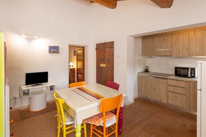 A compact kitchen with wooden cabinets, a microwave, and a dining area with a table and chairs.