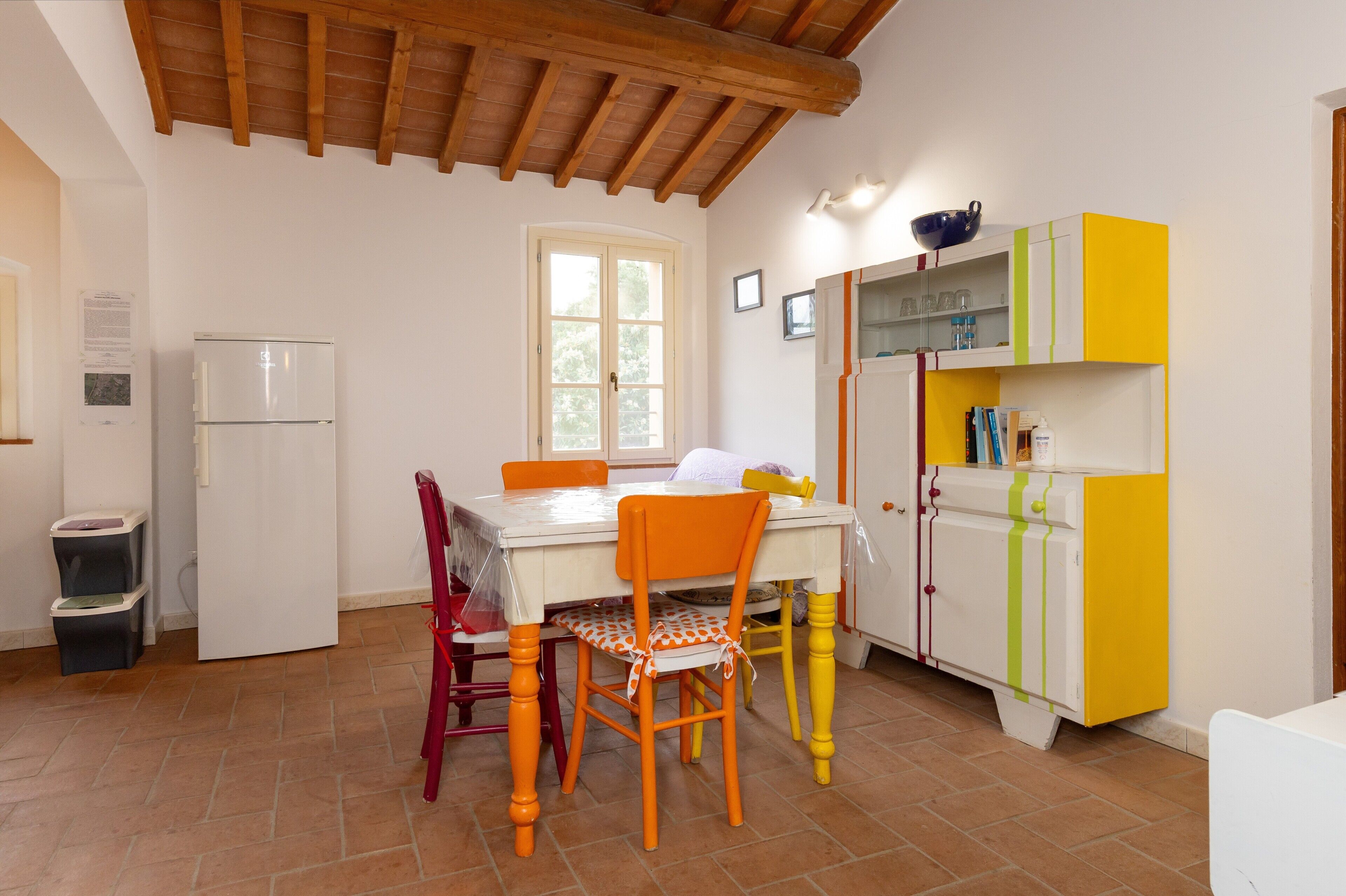 Uma cozinha com geladeira branca, teto de madeira, janela e armário amarelo.