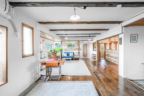 Un hall d’entrée spacieux avec un plancher en bois, un espace de détente central comprenant un canapé et une table, et un escalier menant à un autre niveau.