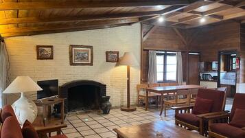 A cozy living room with a fireplace, wooden furniture, and a television.