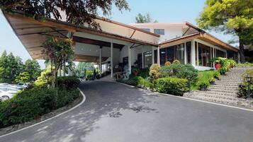 Un edificio moderno con acceso cubierto, una escalera que conduce a la entrada principal y jardines bien cuidados.
