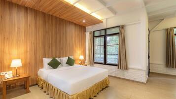 Habitación de hotel con una cama grande, paneles de madera en las paredes, una ventana con cortinas y techo de madera.