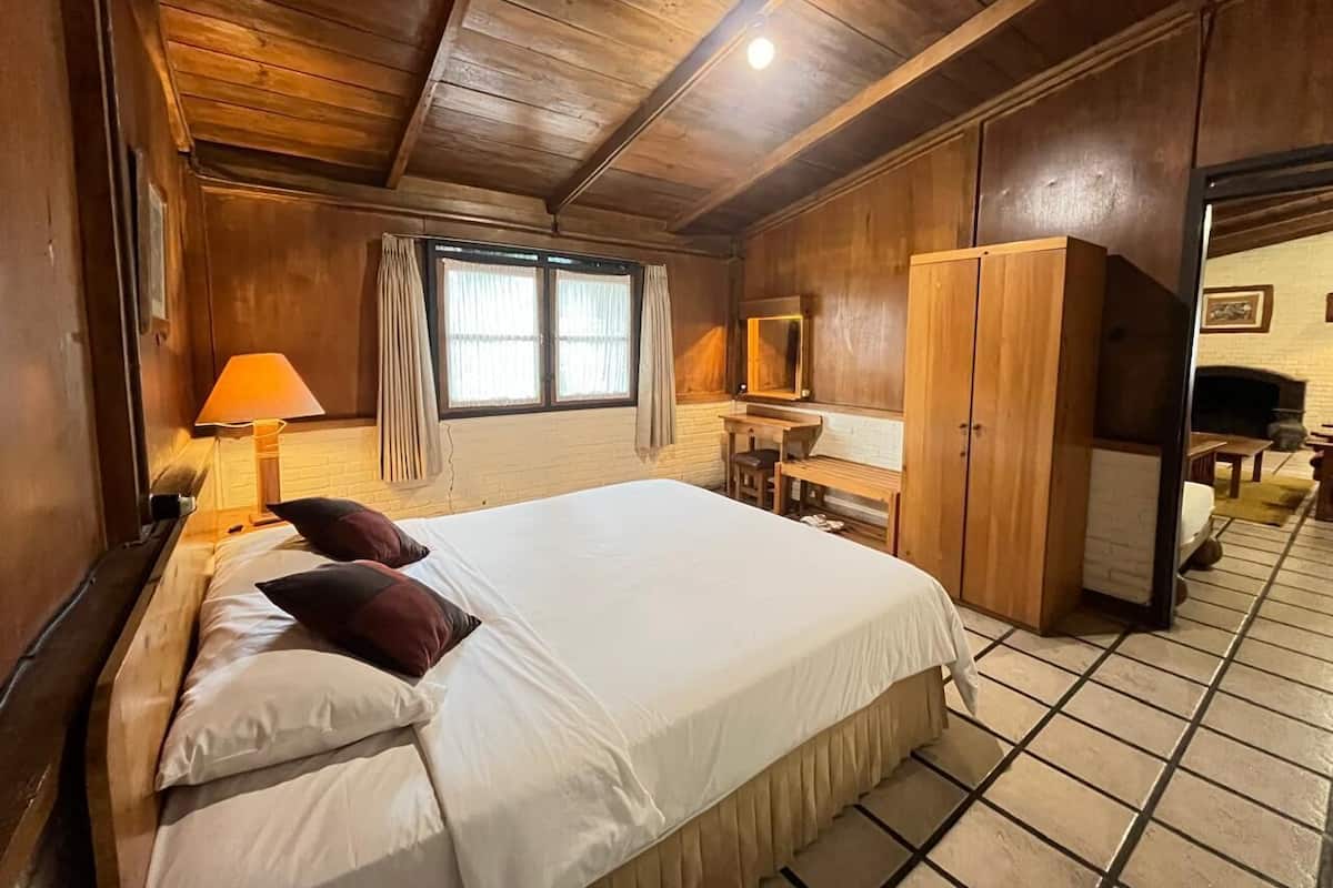 Um quarto com painéis de madeira, uma cama, uma escrivaninha e um guarda-roupa.
