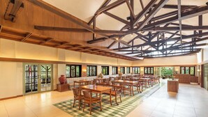 A spacious indoor area with wooden tables and chairs, large windows, and a high ceiling with exposed beams. - Grand Panorama Lembang (Lembang)