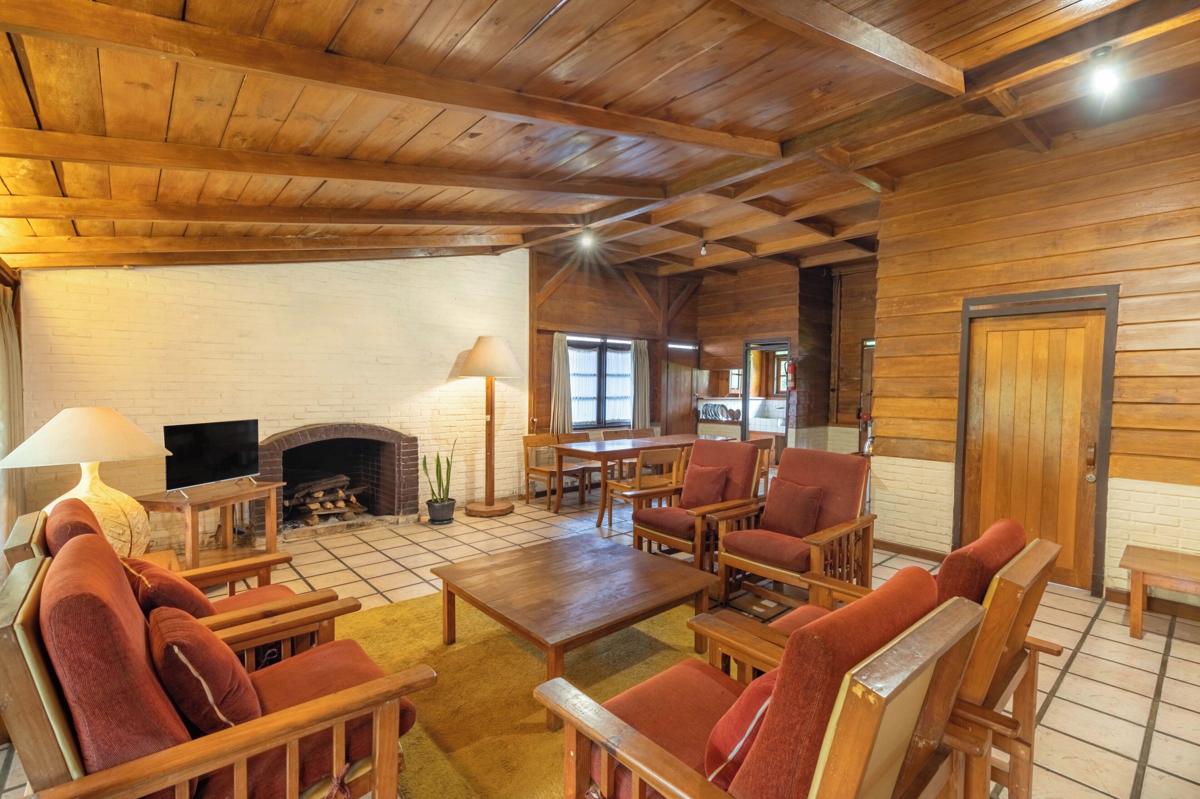 A wooden interior with a fireplace, a television, and seating arrangements.