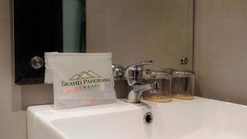 Un lavamanos con encimera blanca, un espejo y una bolsa con la etiqueta "Grand Panorama Lembang".