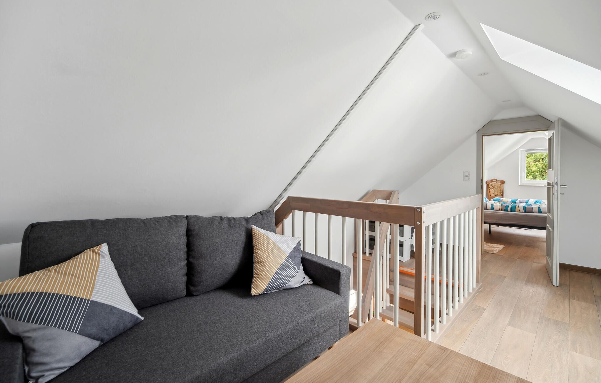 Un dormitorio tipo loft moderno con techo inclinado, una escalera de madera y vistas al exterior.