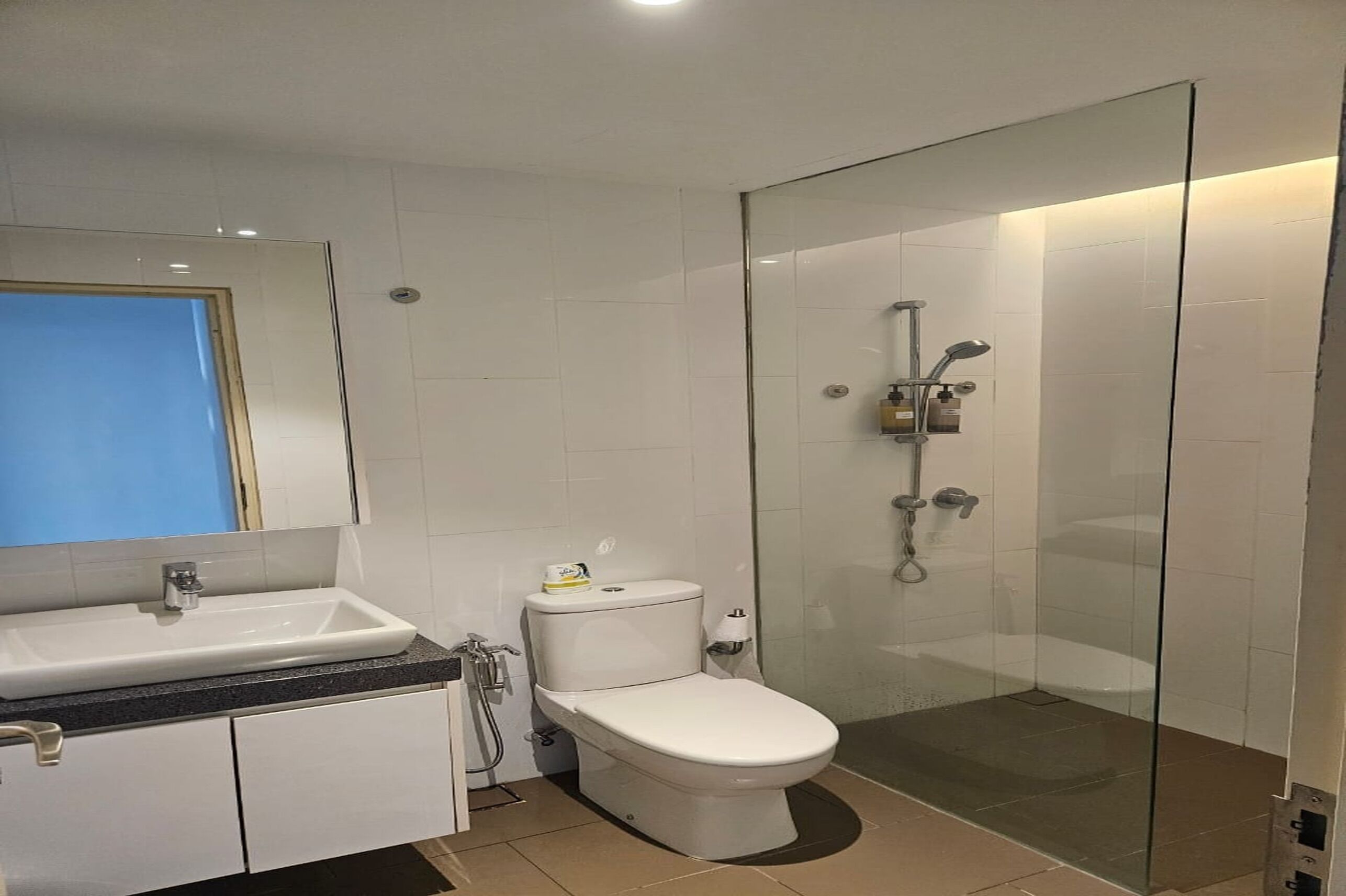 A modern bathroom with a white sink, toilet, and glass-enclosed shower.
