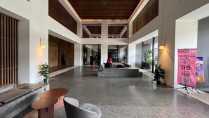 A spacious lobby with a high ceiling, a central seating area, and a promotional stand.