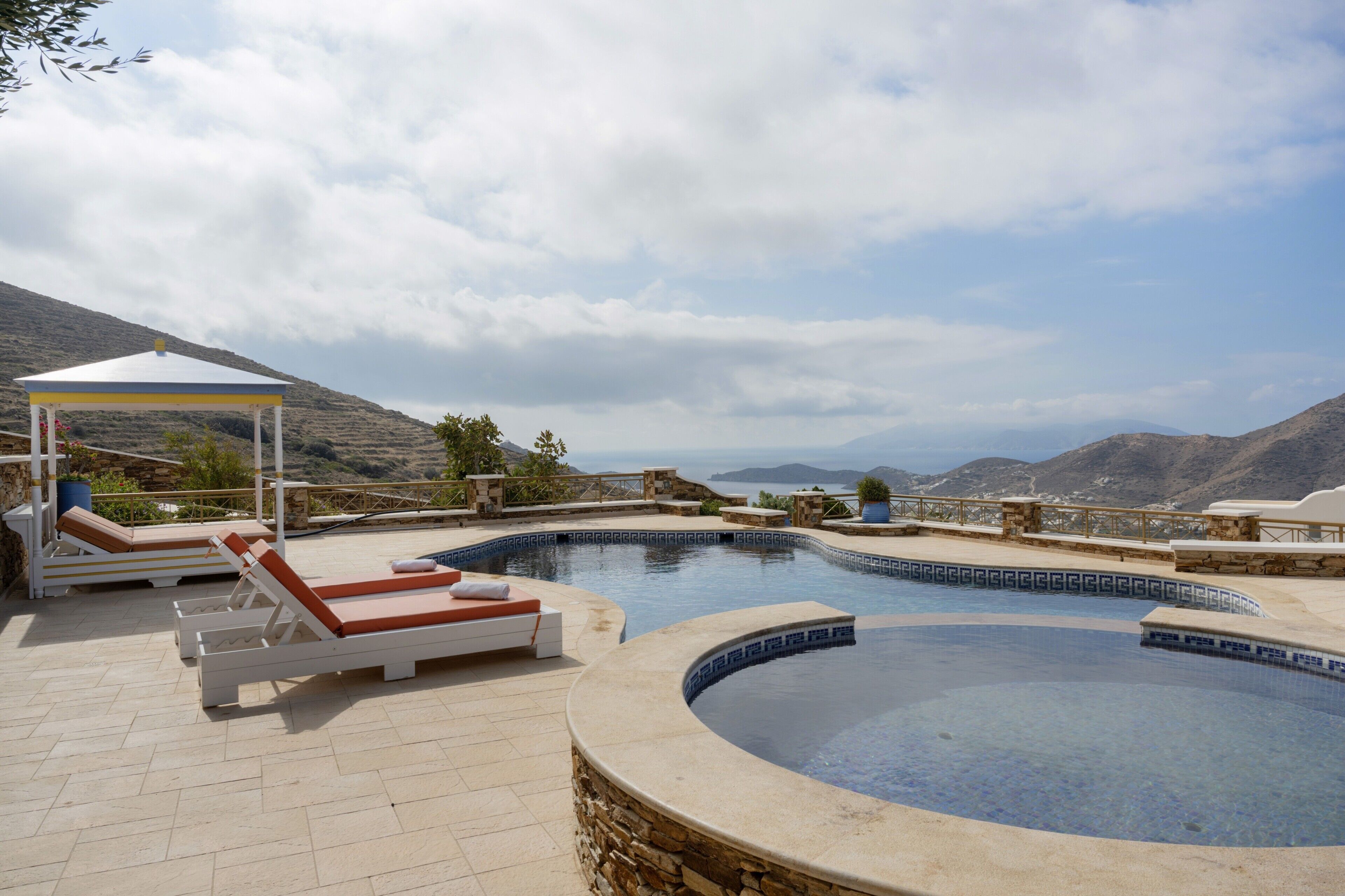 Une piscine bordée de chaises longues, un belvédère et une vue imprenable sur les montagnes.
