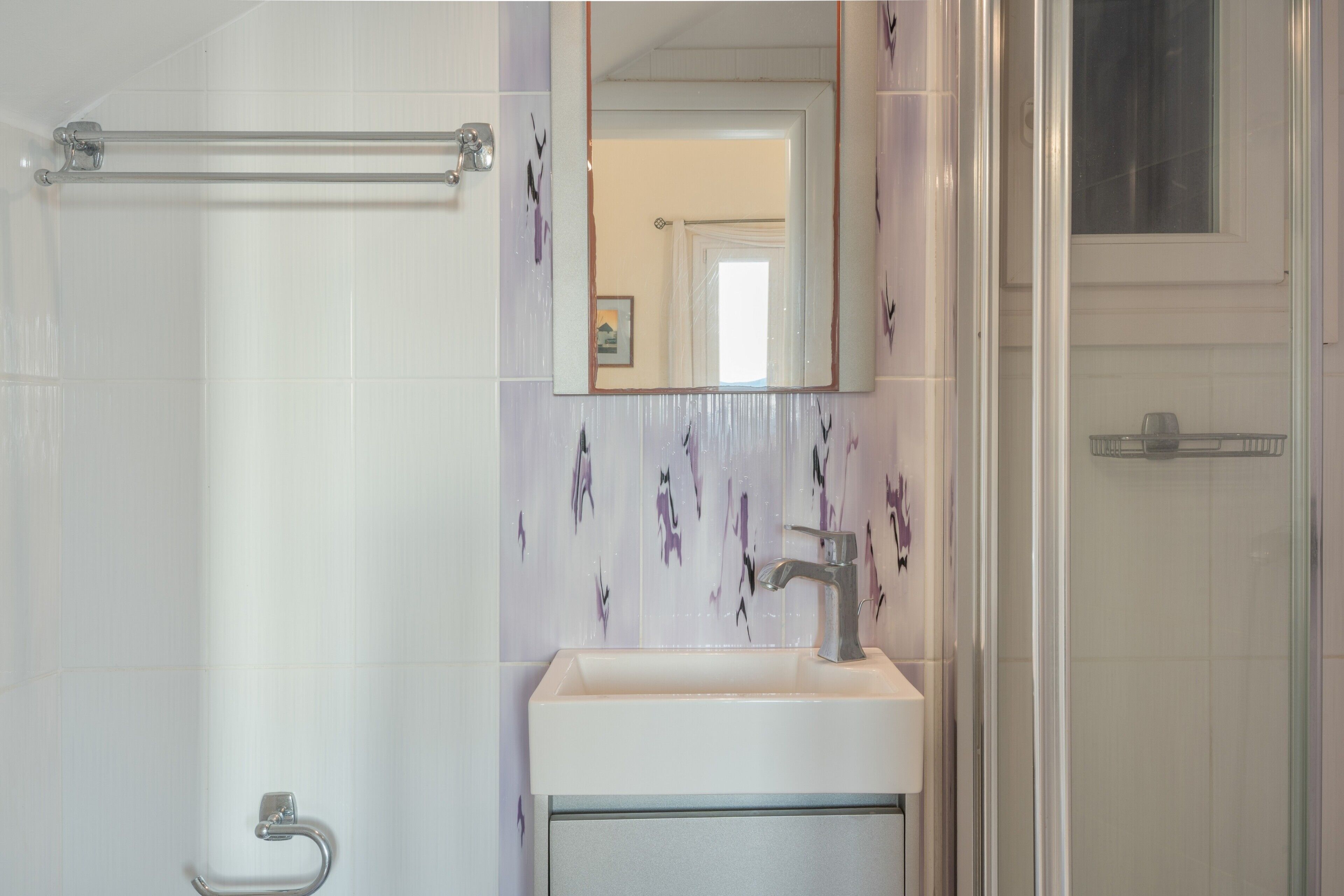 Une salle de bain avec une douche, un lavabo et un miroir.