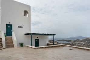 Un edificio blanco con una puerta verde que dice 'BEACH', un área pequeña cubierta y vista a un paisaje costero.