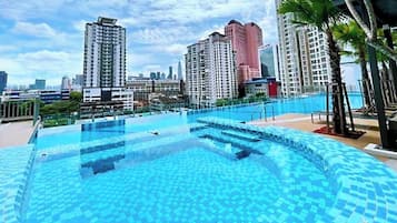 A rooftop swimming pool with a cityscape view, surrounded by high-rise buildings.