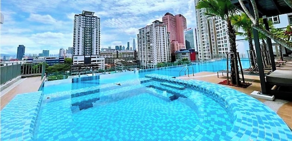 Une piscine sur le toit offrant une vue sur le paysage urbain, entourée d’immeubles de grande hauteur.