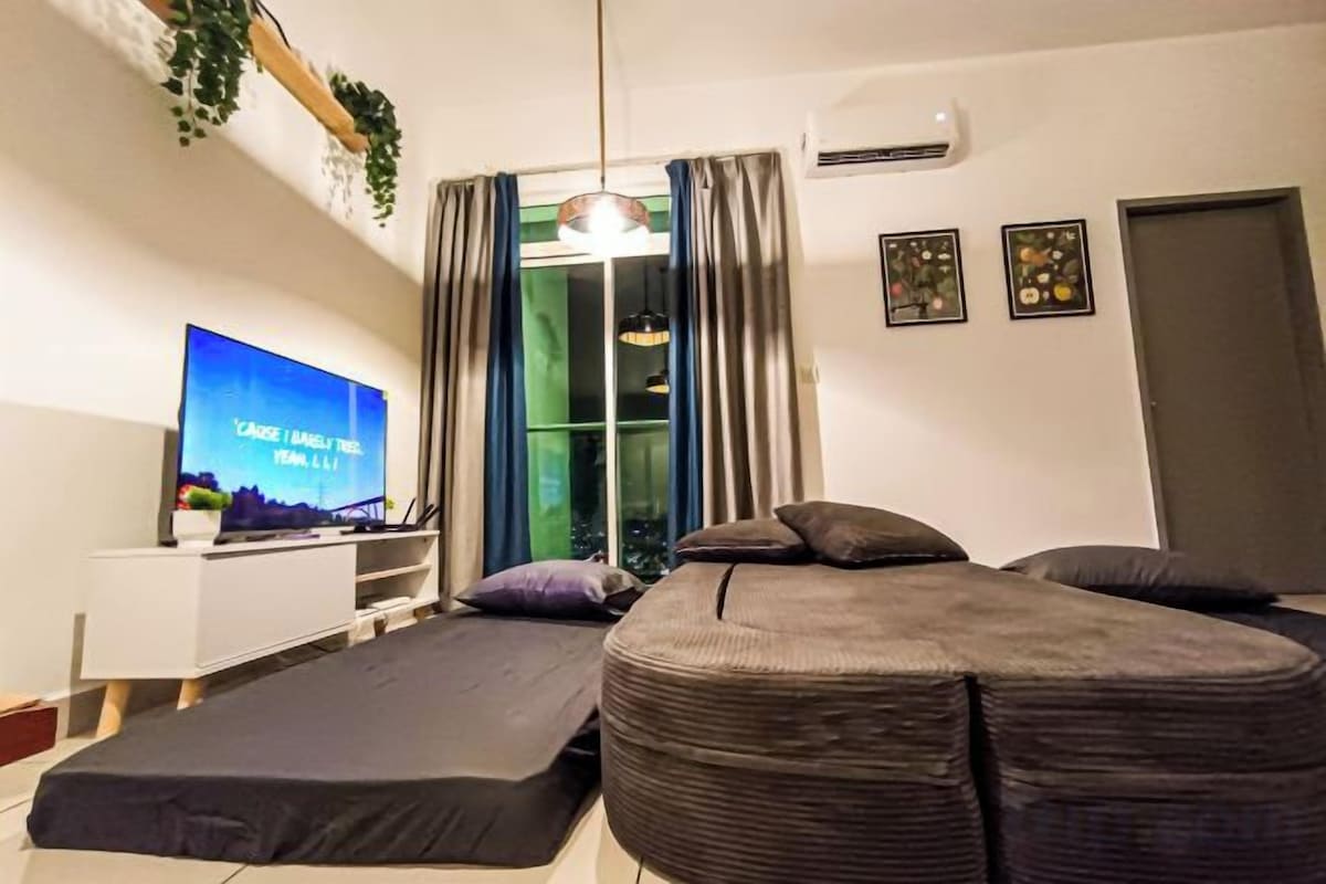 Une petite chambre comprenant un lit, un téléviseur et une fenêtre avec des rideaux.