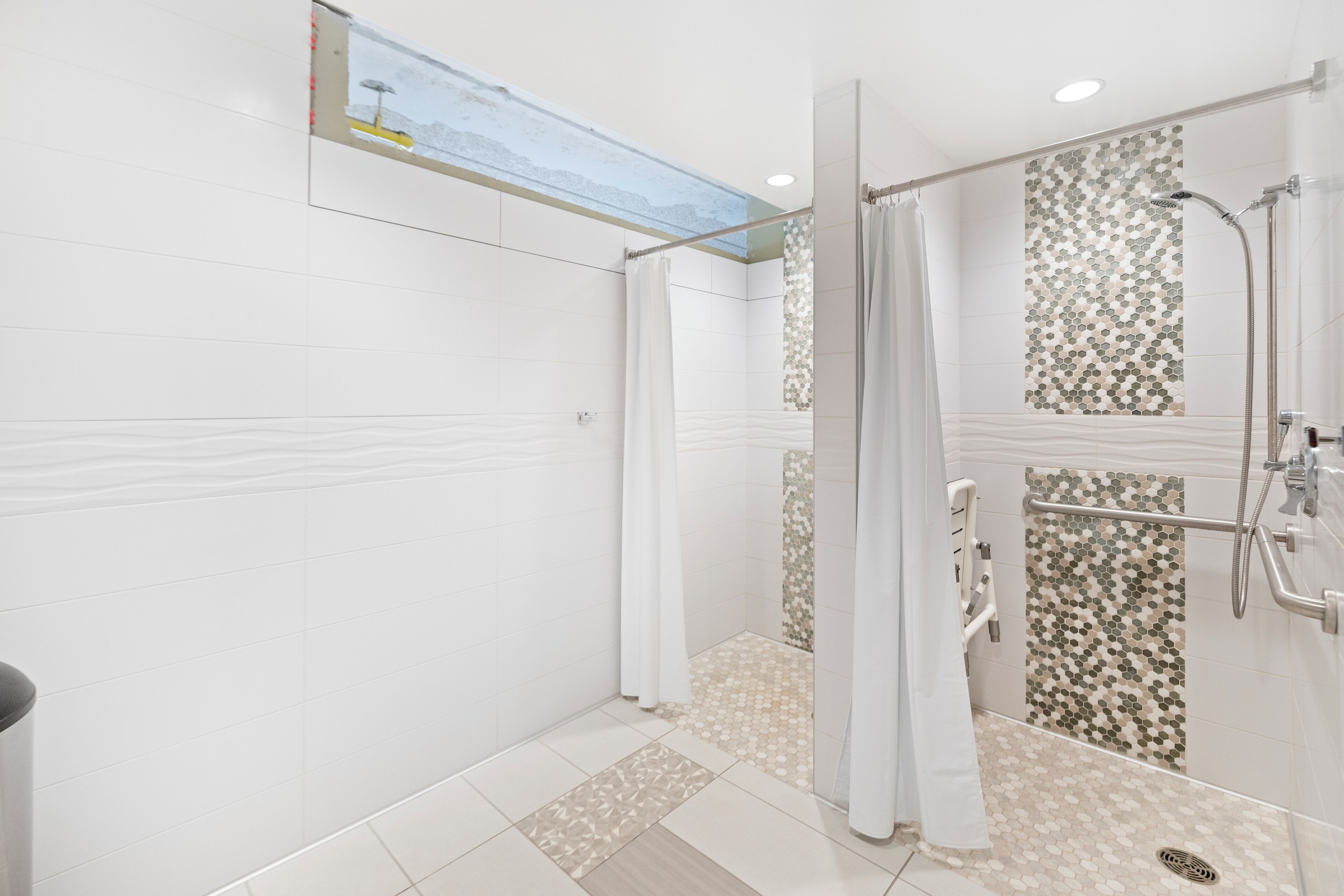 A modern shower area with a glass door, a rain showerhead, and a patterned tile design on the wall.