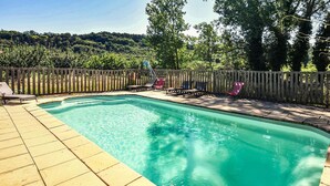 Ein rechteckiger Pool mit Holzterrasse und Liegestühlen.