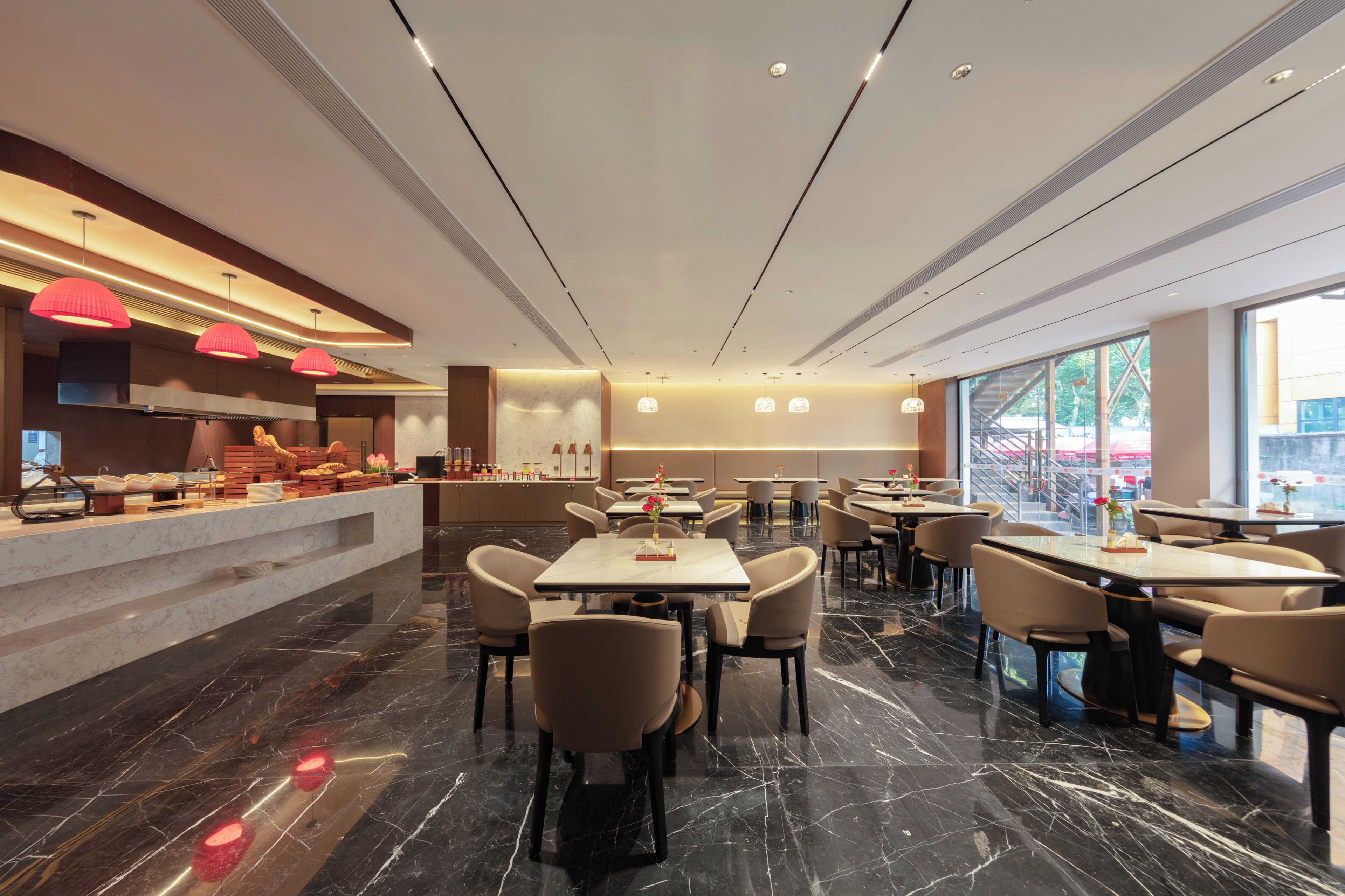Un restaurante moderno con suelos de mármol, varias mesas y sillas, e iluminación colgante.