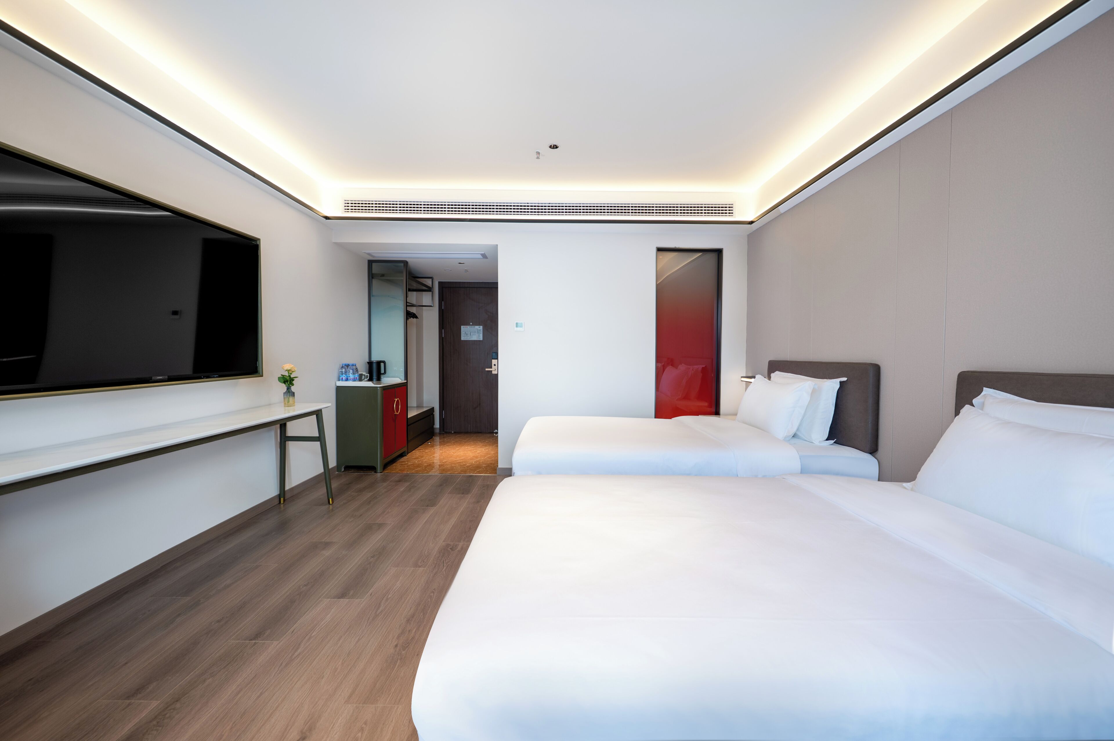 Una habitación de hotel con dos camas, un escritorio, un televisor y una planta pequeña.