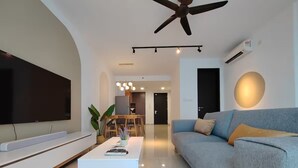 Un salon moderne doté d’un téléviseur à écran plat, d’un ventilateur de plafond et d’un coin repas avec des chaises et une table.