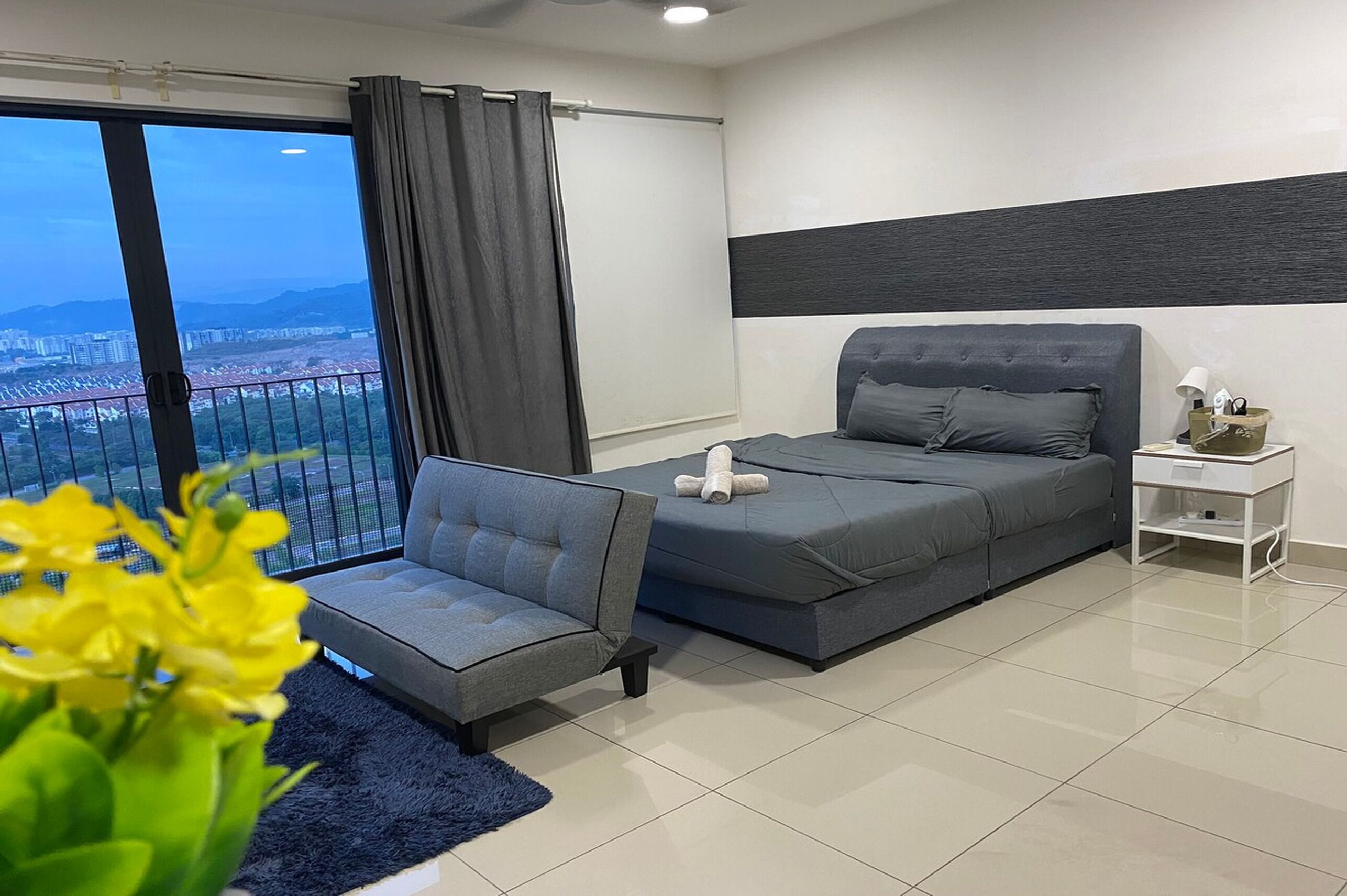 Une chambre moderne avec une grande fenêtre, un canapé, un lit et une table de chevet.