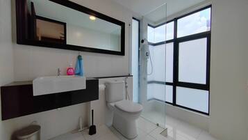 A modern bathroom with a large window, a toilet, a sink, and a mirror.