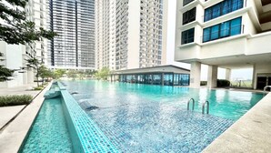 Une piscine à l’eau d’un bleu cristallin, entourée de bâtiments modernes et dotée d’un espace abrité.